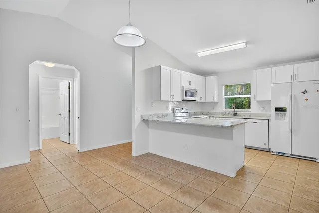 a kitchen with granite countertop white cabinets and stainless steel appliances