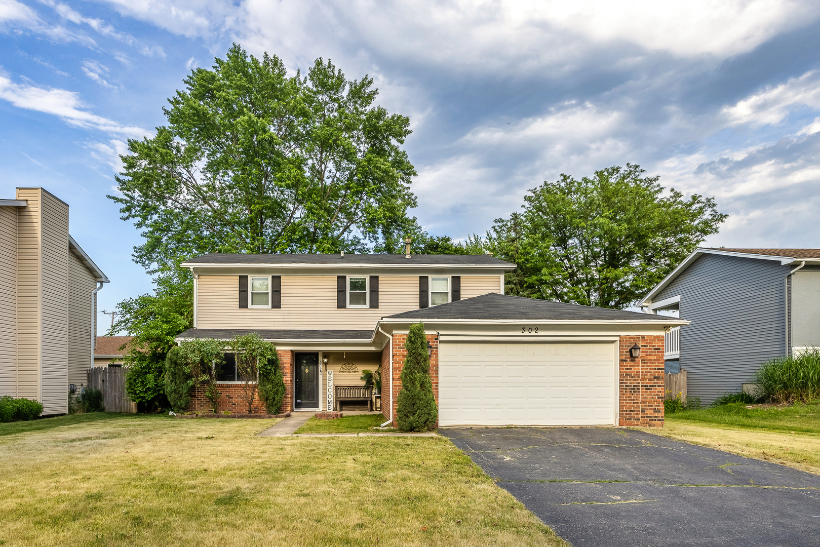 a front view of a house with a garden and trees