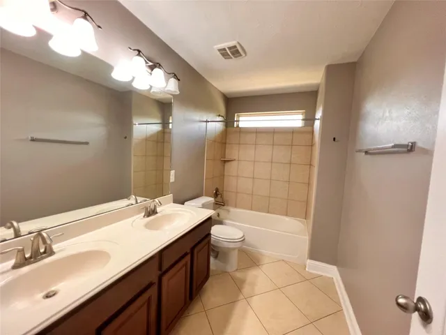 a bathroom with a double vanity sink a toilet and shower