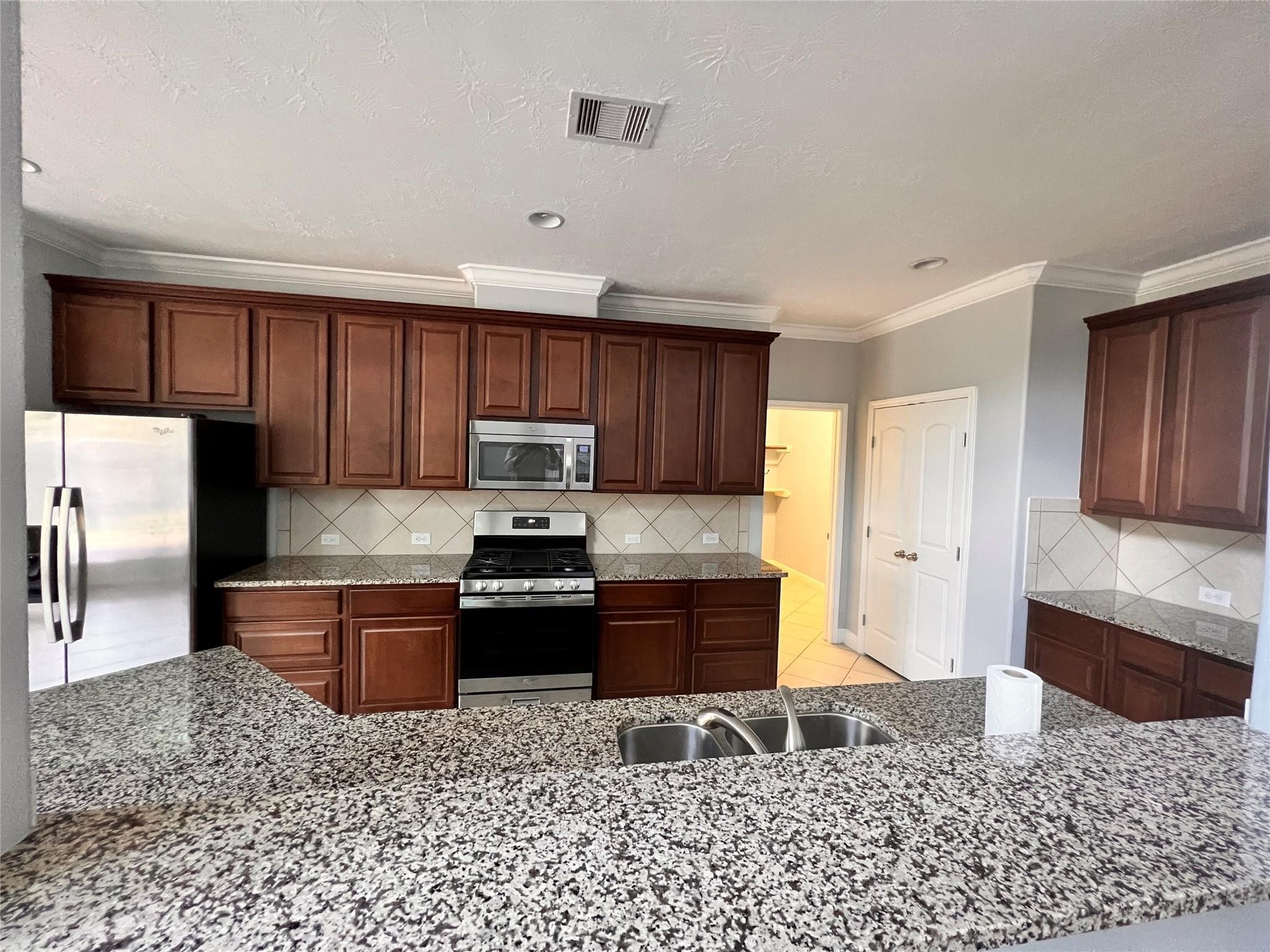 26842 Trinity Trail Cypress, TX 77433 - Photo 9 of 31 a kitchen with stainless steel appliances granite countertop a stove top oven a sink and a refrigerator