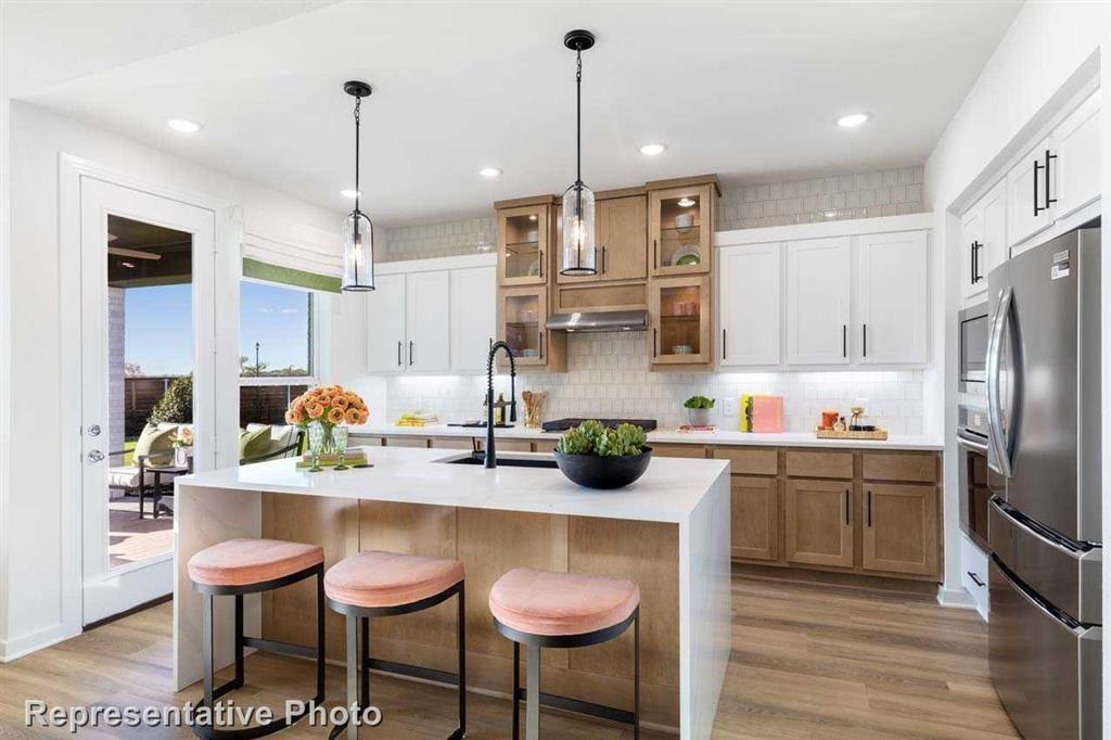 a kitchen with stainless steel appliances granite countertop a sink a stove a refrigerator and chairs