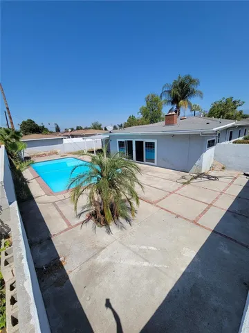 a view of a swimming pool with a lawn chairs under an umbrella