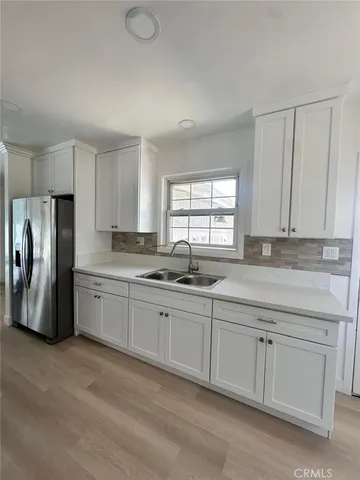 a kitchen with granite countertop a refrigerator sink and cabinets