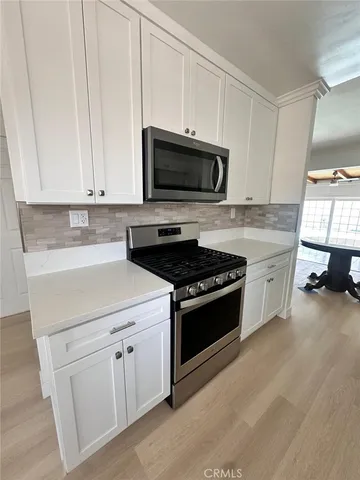 a kitchen with white cabinets and stainless steel appliances