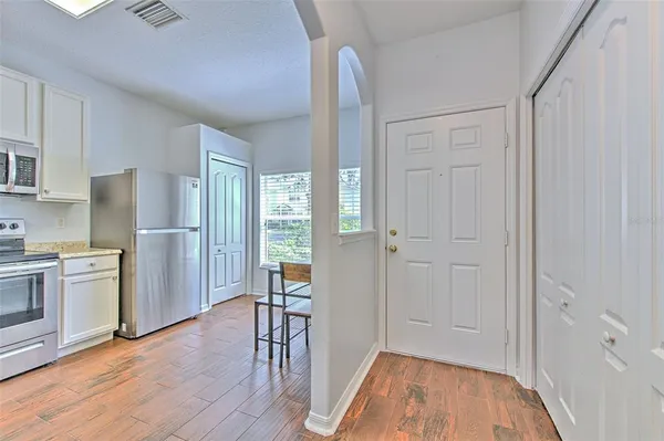 a view of a kitchen with refrigerator and wooden floor