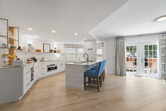 a kitchen with stainless steel appliances kitchen island granite countertop a stove a refrigerator a sink a dining table and chairs with wooden floor