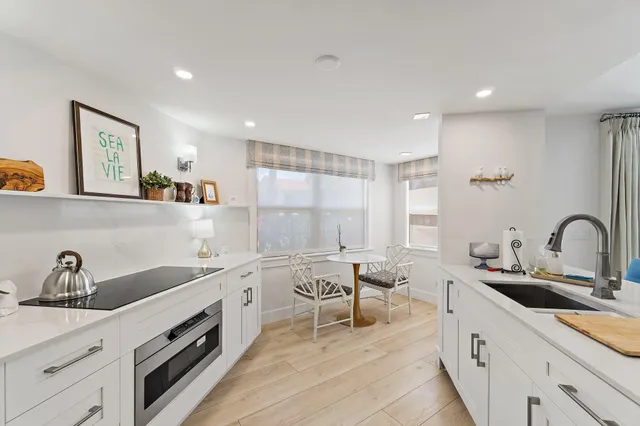 a large white kitchen with a sink and dishwasher a stove with wooden floor