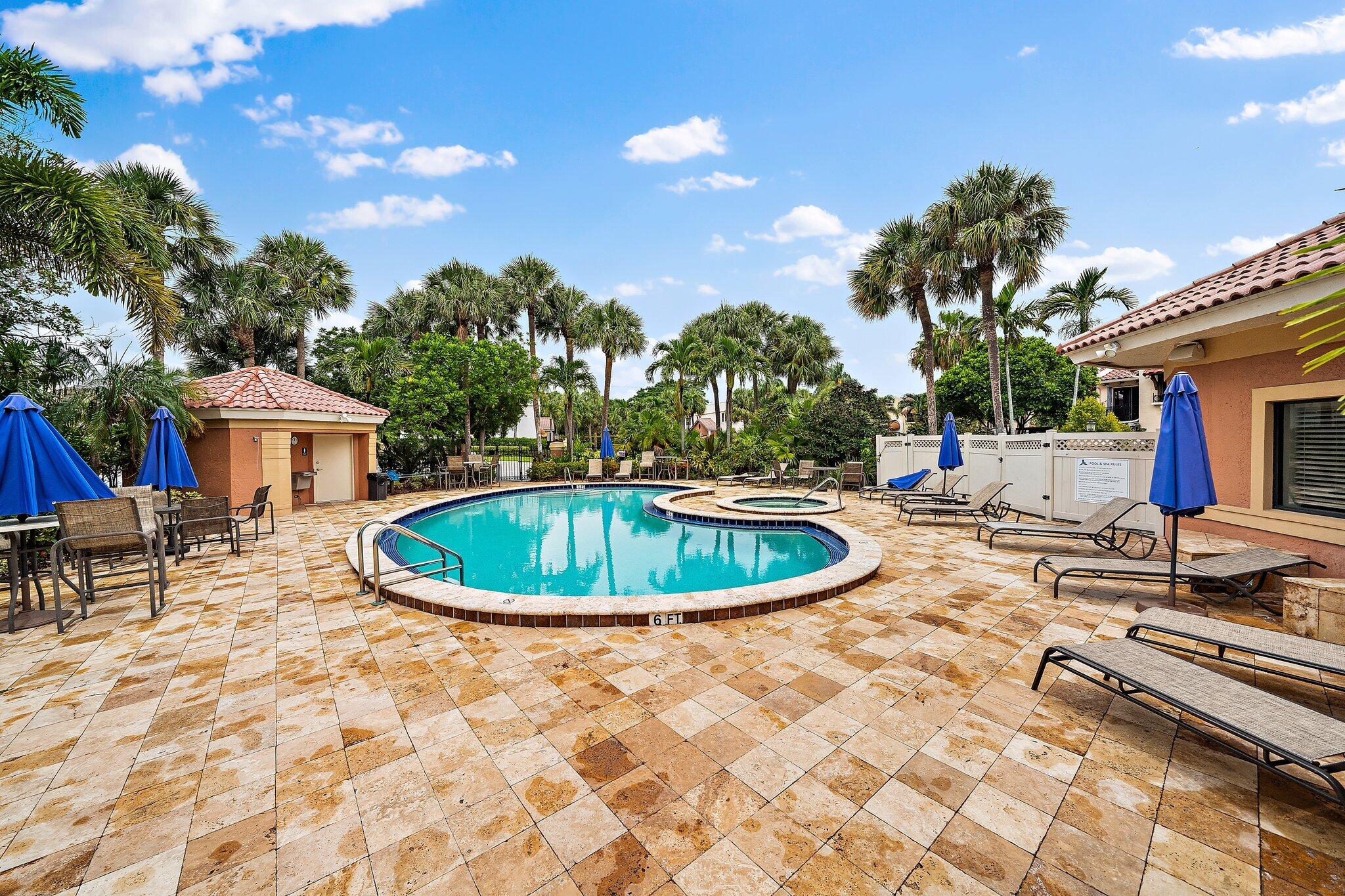 15 Uno Lago Drive, Unit 15 Juno Beach, FL 33408 - Photo 38 of 50 a view of a swimming pool with lawn chairs under an umbrella