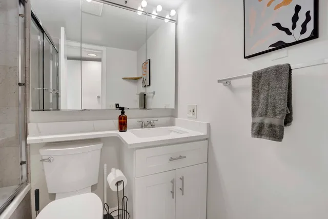 a bathroom with a sink mirror vanity and toilet