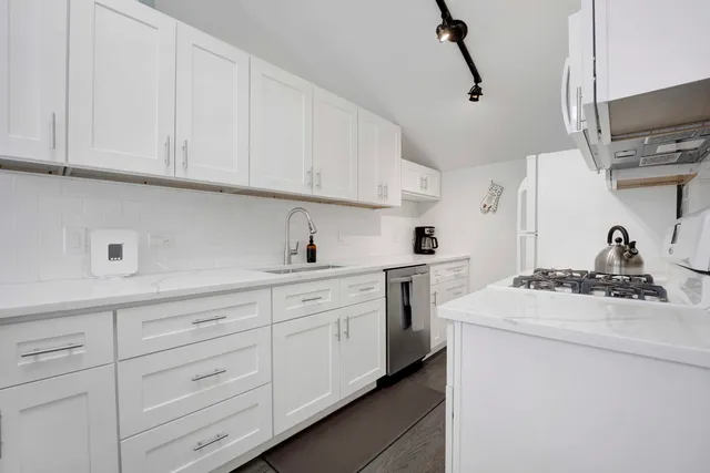 a kitchen with white cabinets and sink
