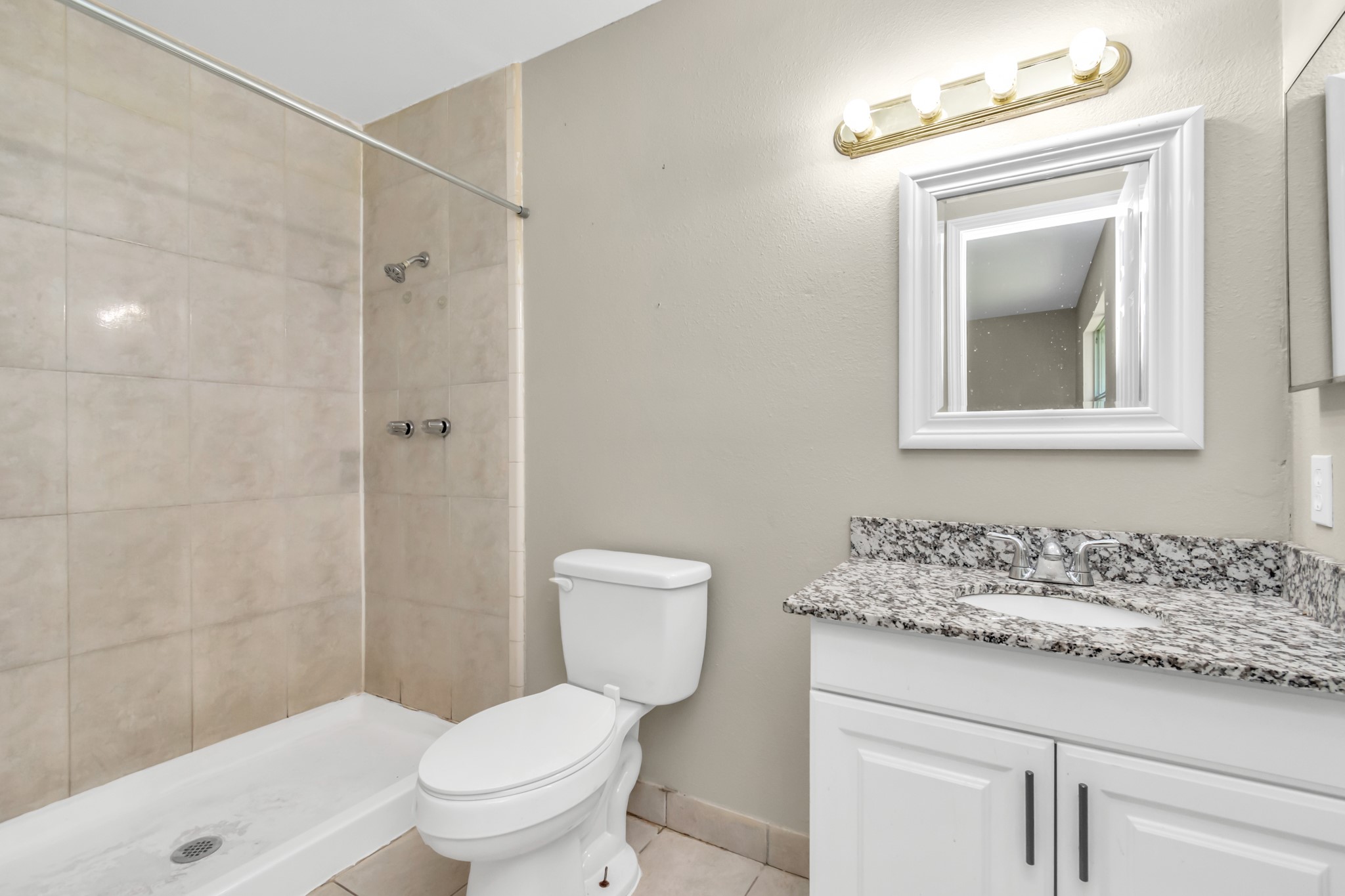 14519 Edenglen Drive Houston, TX 77049 - Photo 28 of 32 a bathroom with a granite countertop toilet a sink and a mirror