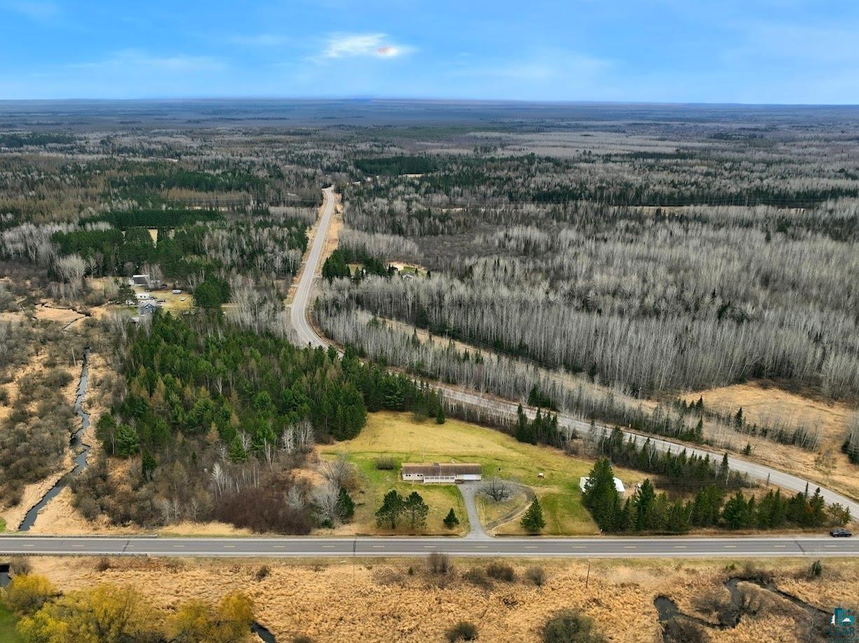 11574 Town Line Road Hibbing, MN 55746 - Photo 40 of 41 Expansive land parcel featuring a single-story dwelling, paved roadway access, mature evergreen trees, a cleared grass area, and surrounding deciduous forest