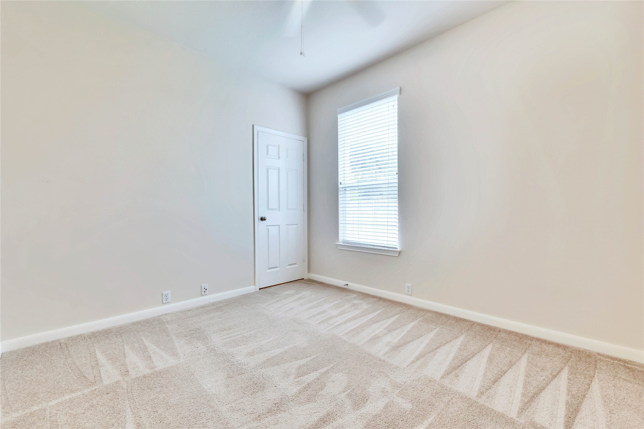 2133 Paradise Ridge Drive Round Rock, TX 78665 - Photo 11 of 22 Neutral-toned room featuring a single window with blinds, light beige carpeting, and a white paneled door