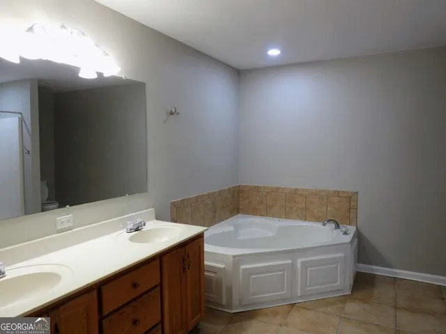 a bathroom with a tub sink and mirror