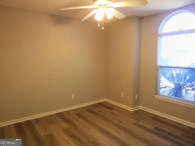 an empty room with wooden floor closet and windows