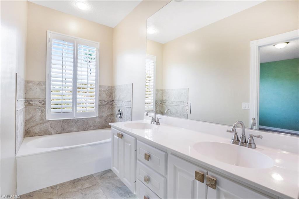 5721 Cove Circle, Unit 36 Naples, FL 34119 - Photo 12 of 32 a bathroom with a double vanity sink and a bathtub