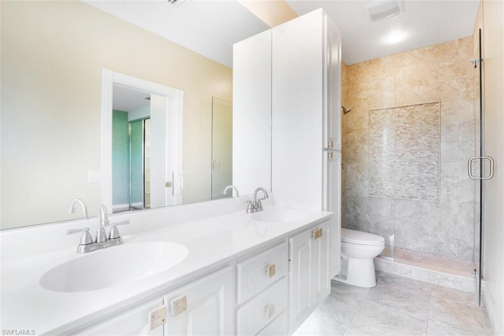 5721 Cove Circle, Unit 36 Naples, FL 34119 - Photo 13 of 32 a bathroom with a double vanity sink toilet and shower