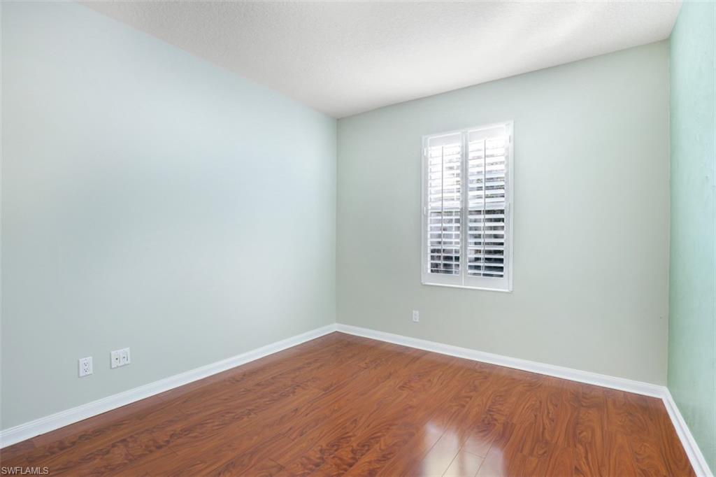 5721 Cove Circle, Unit 36 Naples, FL 34119 - Photo 16 of 32 an empty room with wooden floor and windows