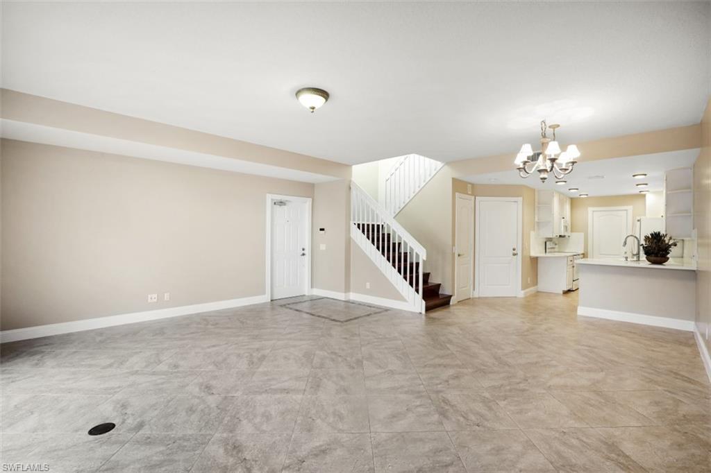 5721 Cove Circle, Unit 36 Naples, FL 34119 - Photo 6 of 32 an empty room with a chandelier and a flat screen tv
