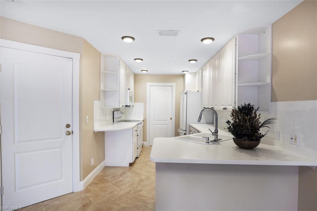 5721 Cove Circle, Unit 36 Naples, FL 34119 - Photo 9 of 32 a kitchen with sink a potted plant and cabinets