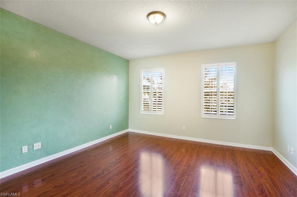5721 Cove Circle, Unit 36 Naples, FL 34119 - Photo 10 of 32 an empty room with wooden floor and windows