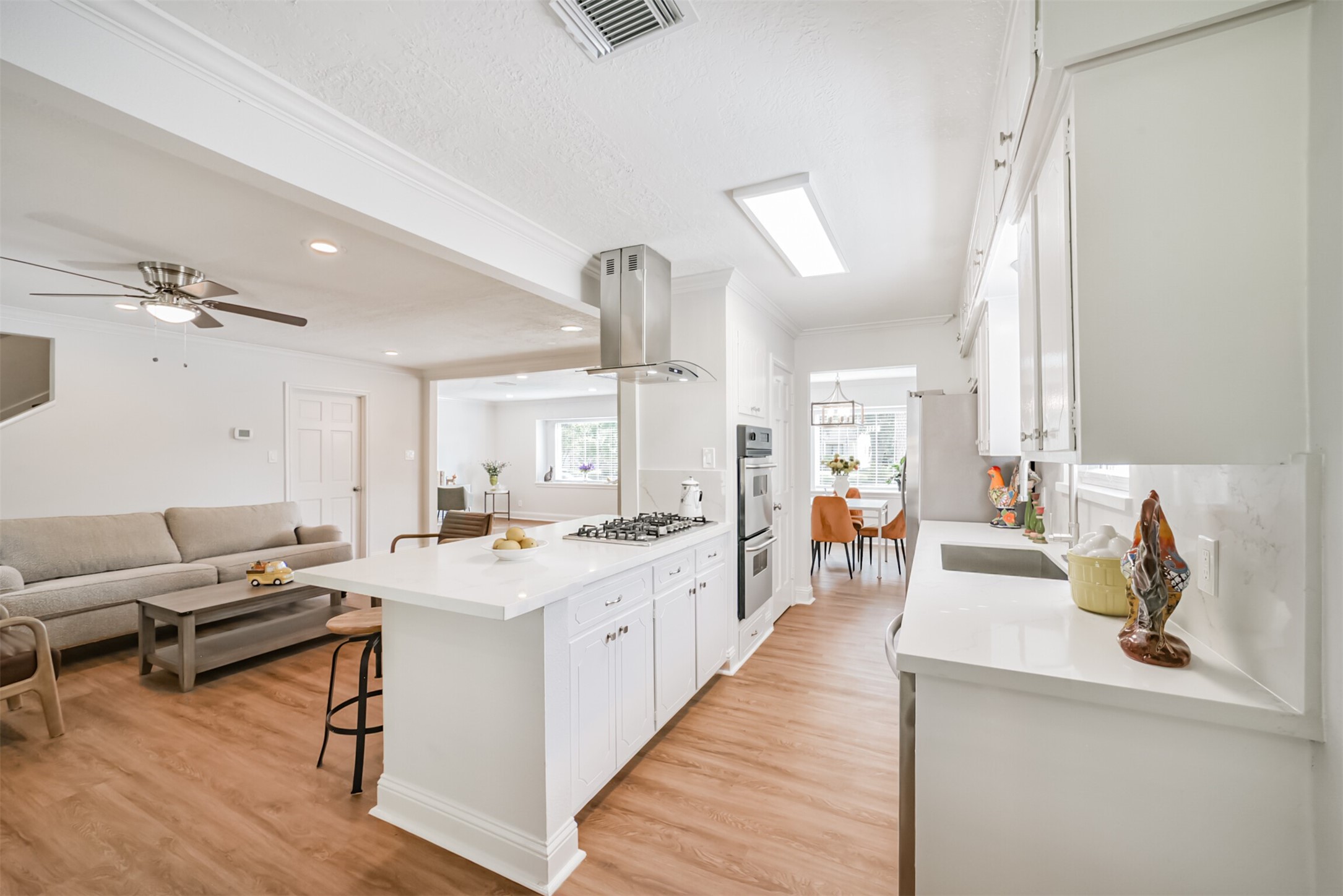 3319 Springrock Lane Houston, TX 77080 - Photo 6 of 41 a large white kitchen with a stove a sink dishwasher and a dining table with wooden floor