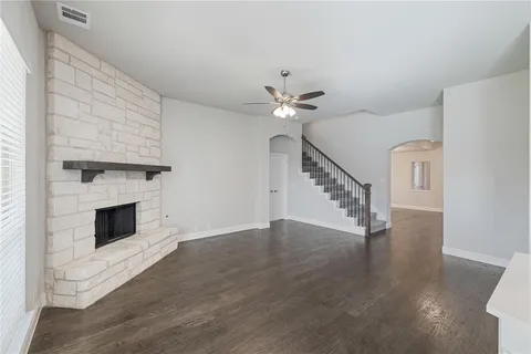a view of an empty room with wooden floor and a fireplace