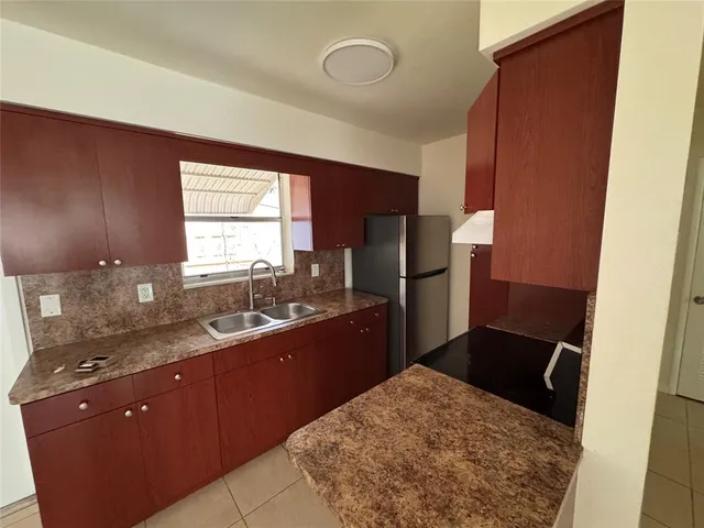 a kitchen with a sink a refrigerator and wooden cabinets