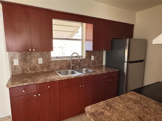 a view of a refrigerator in kitchen and an empty room