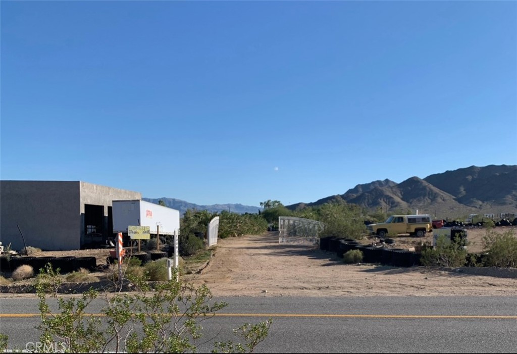 10163 Nipton Road Nipton, CA 92364 - Photo 2 of 4 a view of a house with a yard and table and chairs under an umbrella