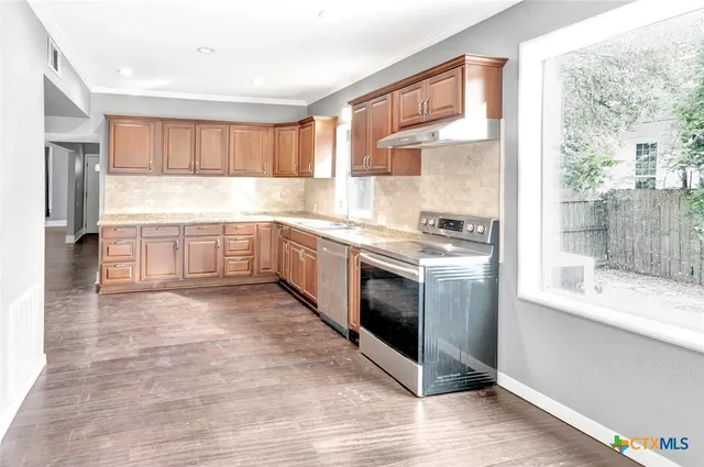 a kitchen with stainless steel appliances granite countertop a stove a sink and a refrigerator