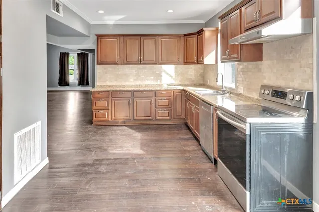 a kitchen with stainless steel appliances granite countertop a stove a sink and a refrigerator