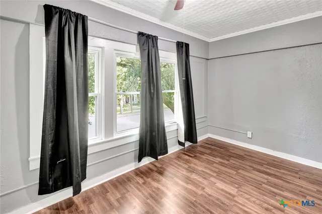 a view of an empty room with wooden floor and closet