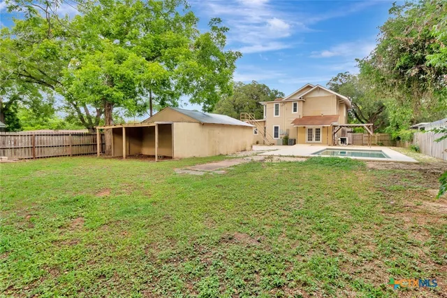 a view of a white house with a yard and table and chairs under an umbrella