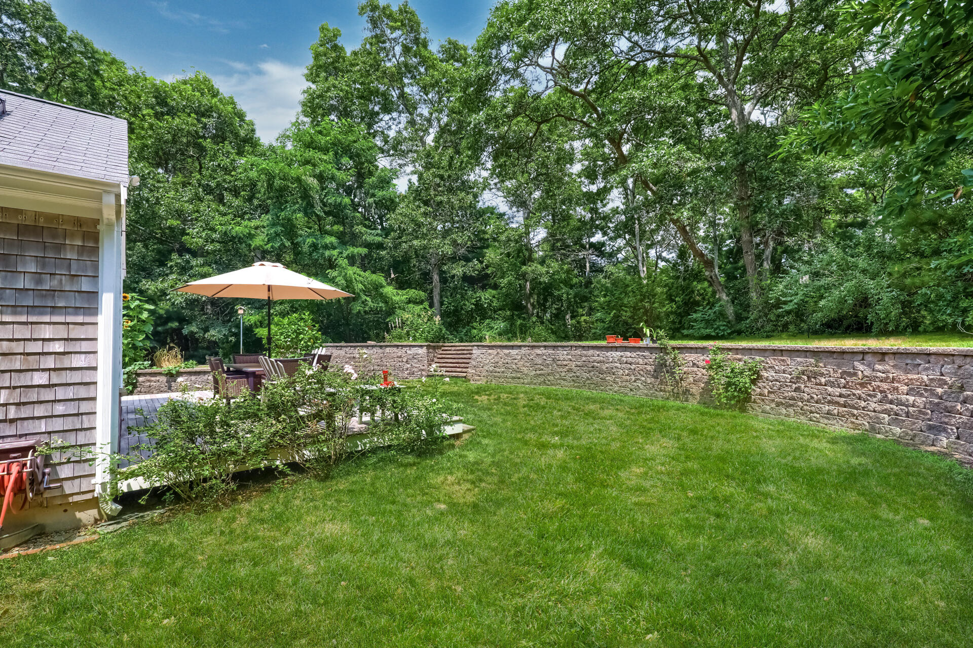 626 River Road Marstons Mills, MA 02648 - Photo 21 of 27 a backyard of a house with table and chairs under an umbrella