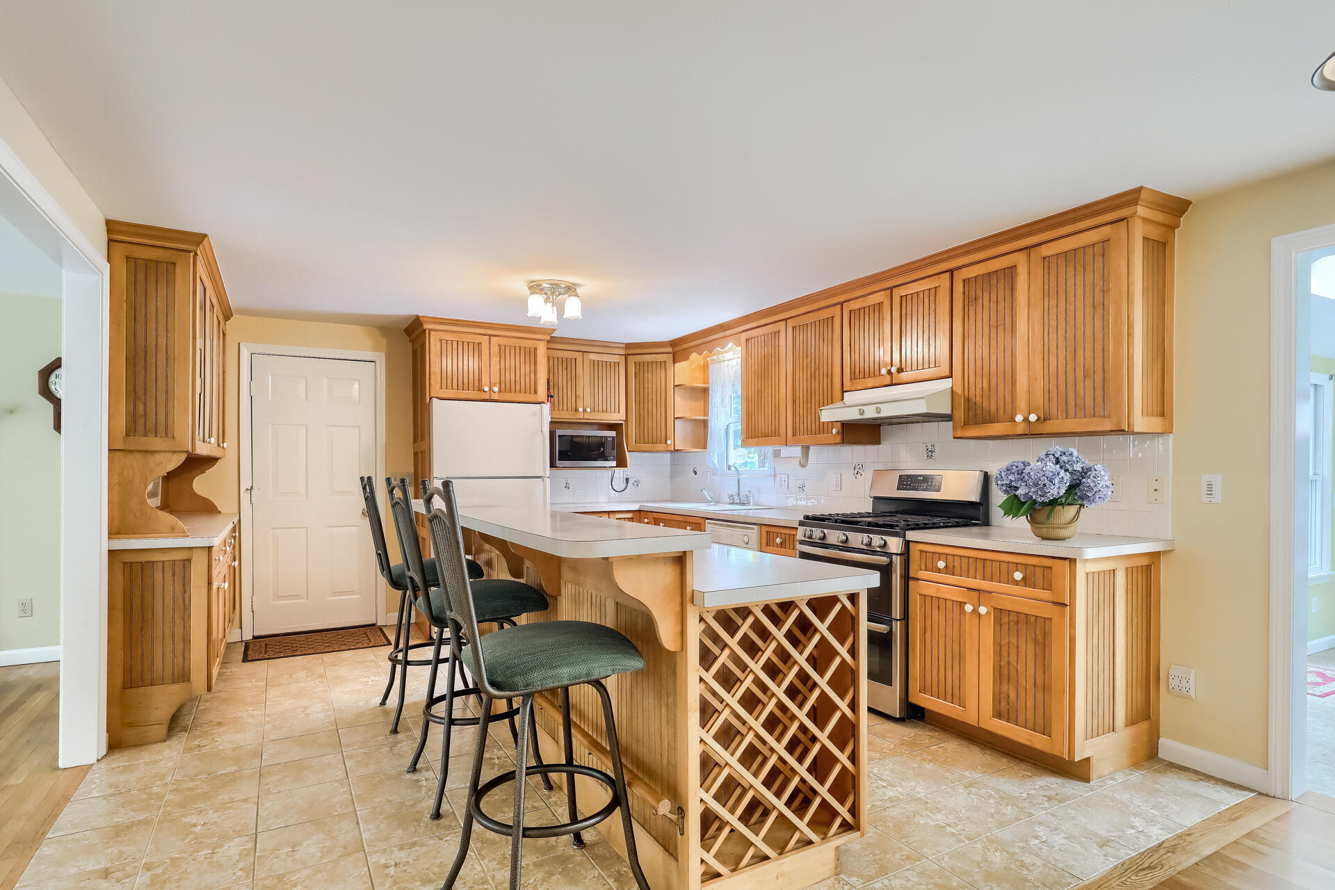 626 River Road Marstons Mills, MA 02648 - Photo 5 of 27 a kitchen with stainless steel appliances granite countertop a stove top oven a sink a refrigerator with a dining table and chairs with wooden floor