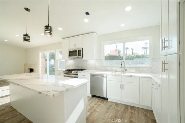 a kitchen with stainless steel appliances granite countertop a sink a stove a refrigerator a center island and cabinets