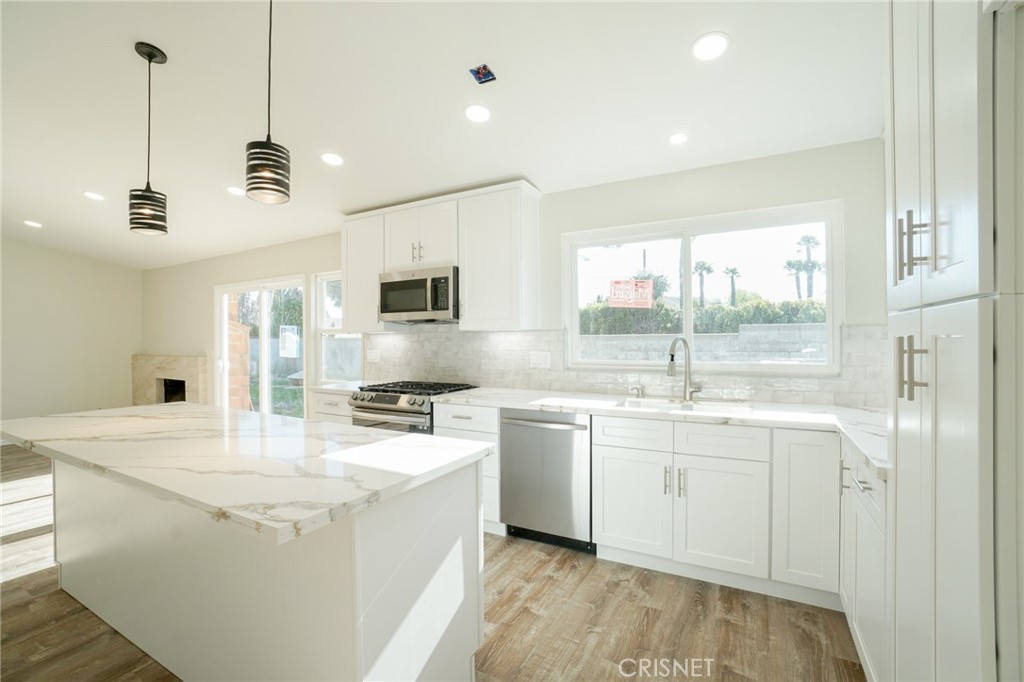 a kitchen with stainless steel appliances granite countertop a sink a stove a refrigerator a center island and cabinets