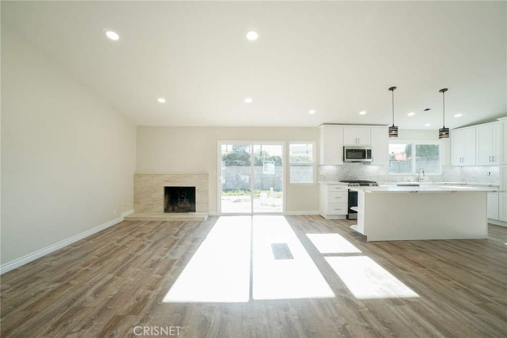 1108 Waltham Road Simi Valley, CA 93065 - Photo 9 of 25 a large white kitchen with a stove a sink dishwasher and a fireplace with wooden floor