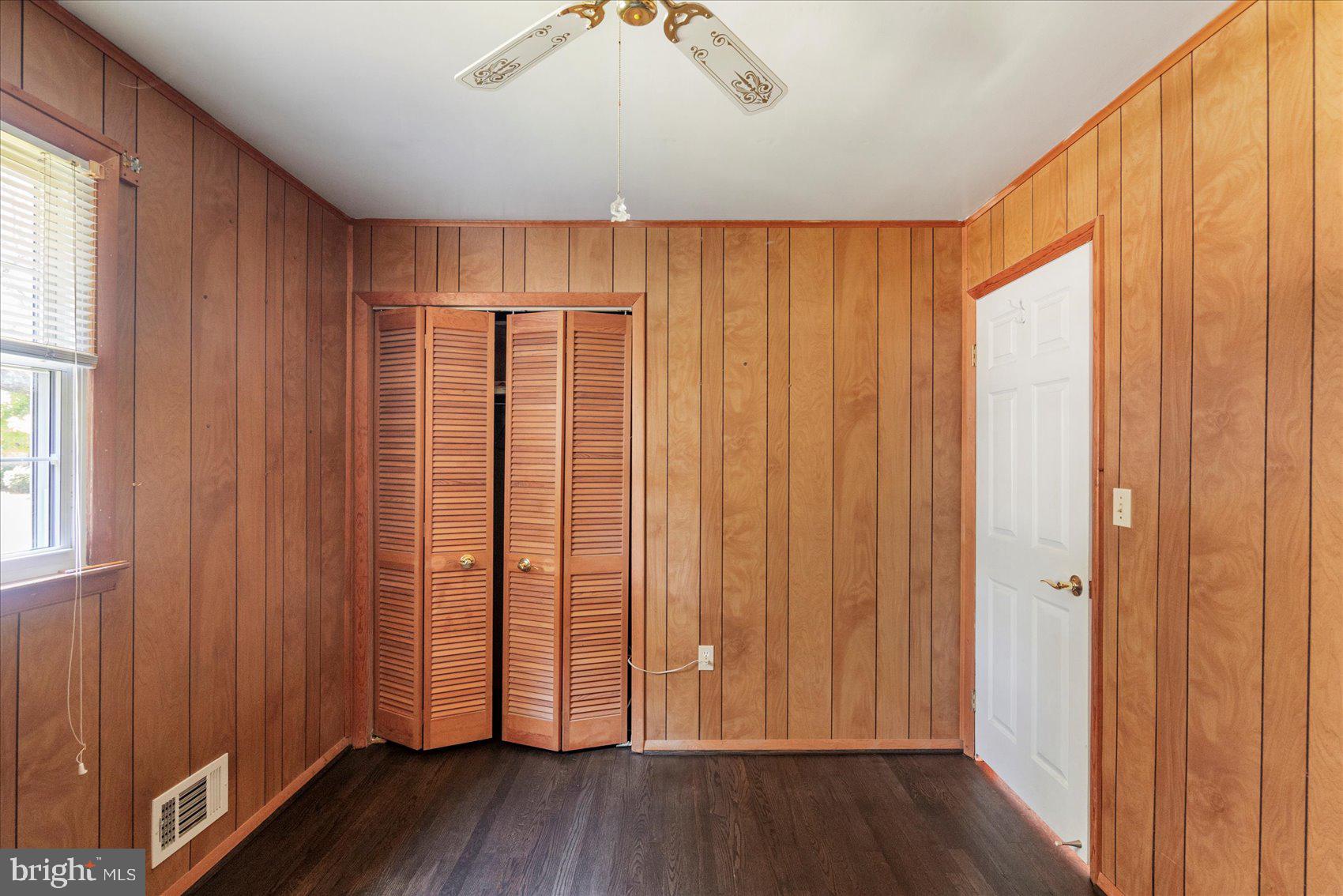 8261 Spring Knoll Drive Pasadena, MD 21122 - Photo 23 of 49 an empty room with wooden floor and windows with curtains