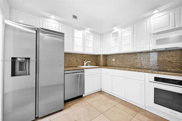 a kitchen with a refrigerator sink and cabinets