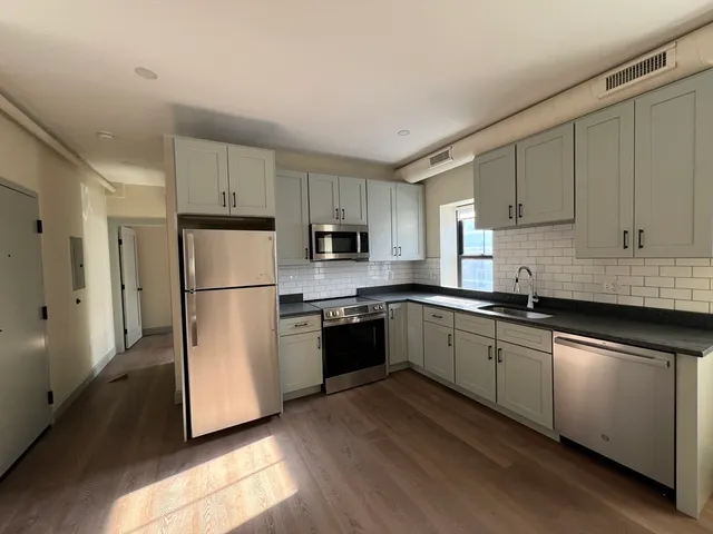 a kitchen with a refrigerator a microwave a sink and cabinets
