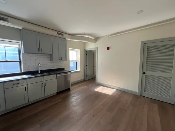 a kitchen with granite countertop stainless steel appliances a sink window and cabinets