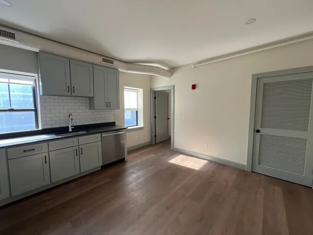 a kitchen with granite countertop stainless steel appliances a sink window and cabinets