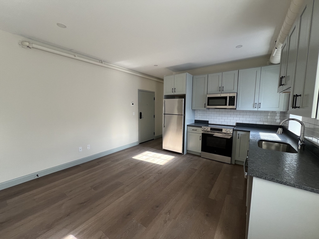 160 Seabury Street, Unit 11 Fall River, MA 02720 - Photo 3 of 10 a kitchen with wooden floors and stainless steel appliances