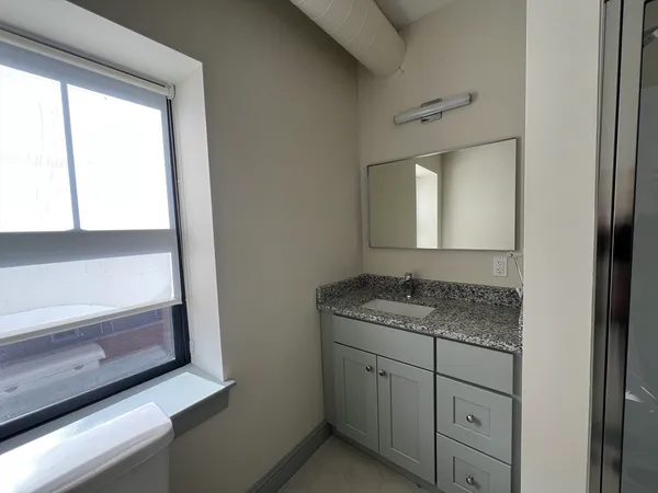 a bathroom with a granite countertop sink and mirror
