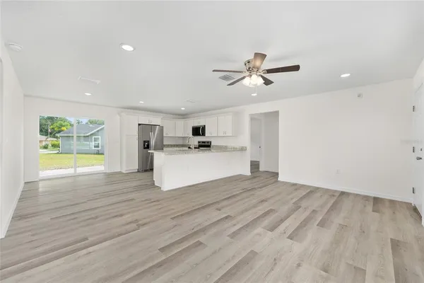 a view of a kitchen with wooden floor and a ceiling fan