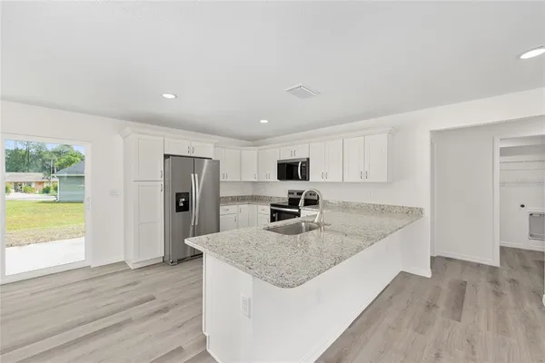 a kitchen with stainless steel appliances granite countertop a sink dishwasher and a refrigerator with wooden floor
