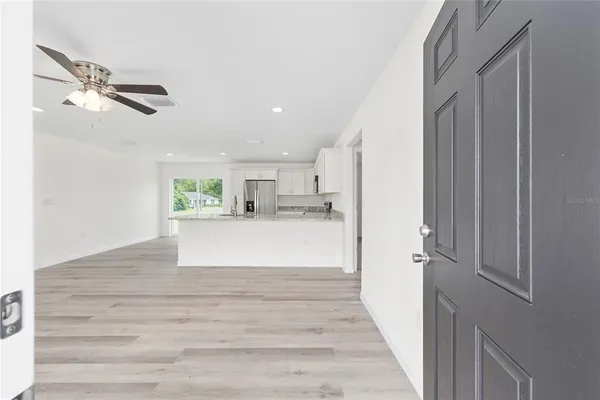 a view of a hallway to a bedroom with wooden floor and windows