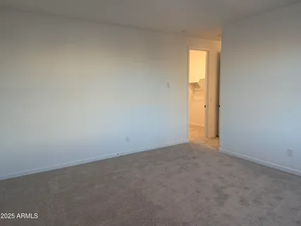 a view of an empty room with wooden floor and a kitchen